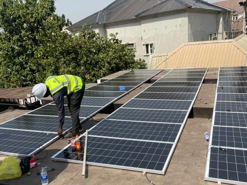 An Endlos Energy technician bolting panels into their frames on a rooftop array in Abuja