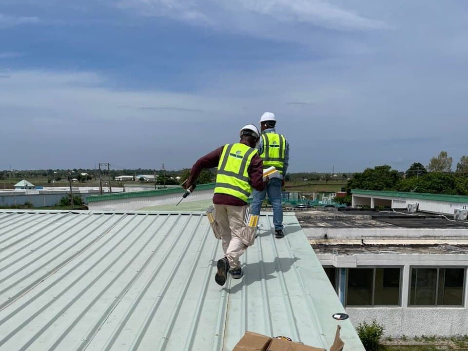 Two Endlos Energy engineers walking a metal factory roof to audit it before installation