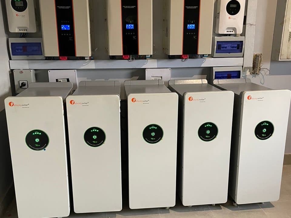 Five inverters mounted above five lithium battery units, commissioned and running