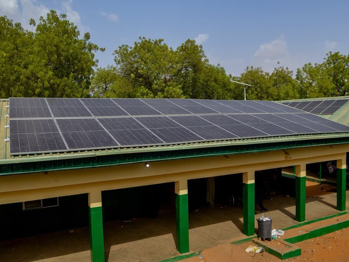 A finished solar array running the length of a long building's roof above a covered walkway