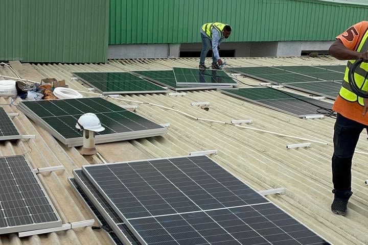 Engineers laying panels across the metal roof of a large commercial building